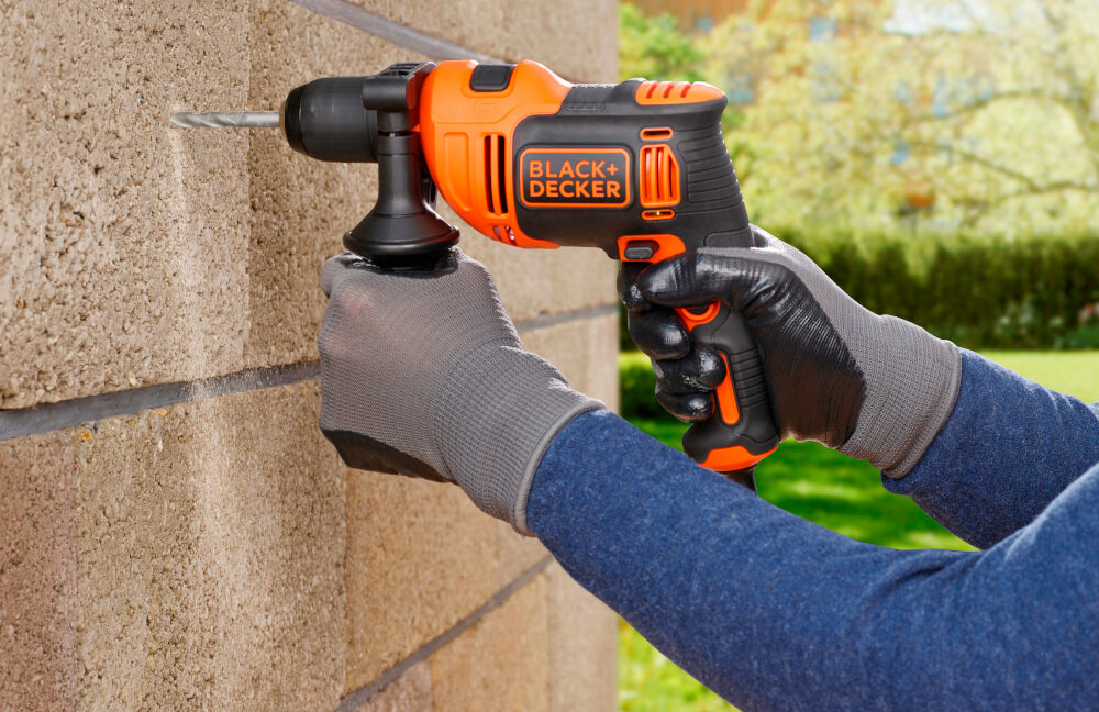 Wiertarka udarowa BLACK&DECKER BEH710-QS ogród ściana domu ściana z dużych cegieł osoba wierci otwór w ścianie w tle trawnik drzewa rośliny silnik szczotkowy do 47600 uderzeń na minutę szybkie i skuteczne wiercenie wysoki moment obrotowy płynne prowadzenie wiertła precyzyjne rezultaty