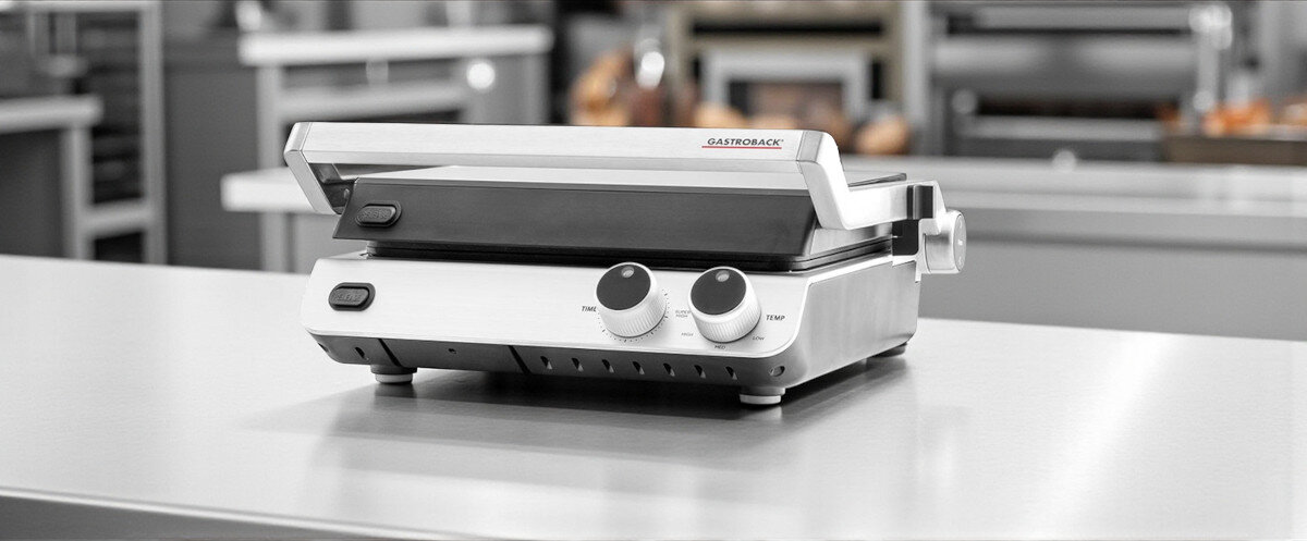 Grill elektryczny GASTROBACK 42537, automatyczne, dźwięk, unikanie, przypalenia, timer, grill stoi na na stalowym blacie w kuchni restauracyjnej