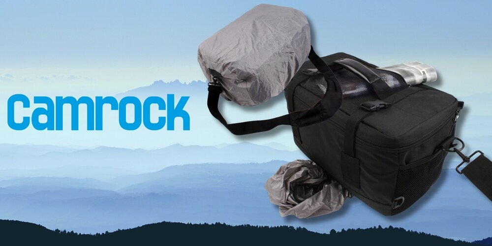 Torba Camrock Tank X60 z pokrowcem przeciwdeszczowym i gazetą  w bocznej kieszeni, na tle górskiego krajobrazu