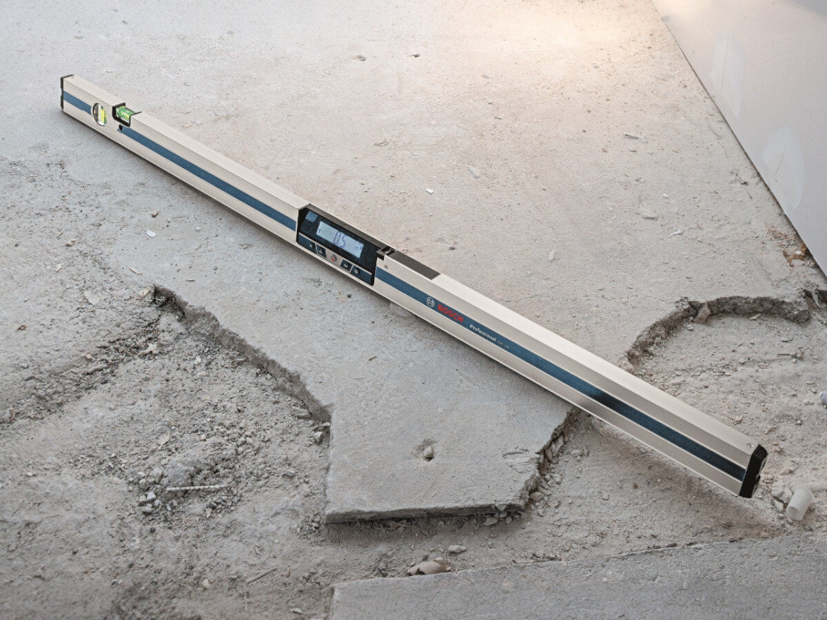 Poziomnica elektroniczna leży na betonowej powierzchni. Na urządzeniu widoczne jest logo BOSCH oraz wyświetlacz cyfrowy.