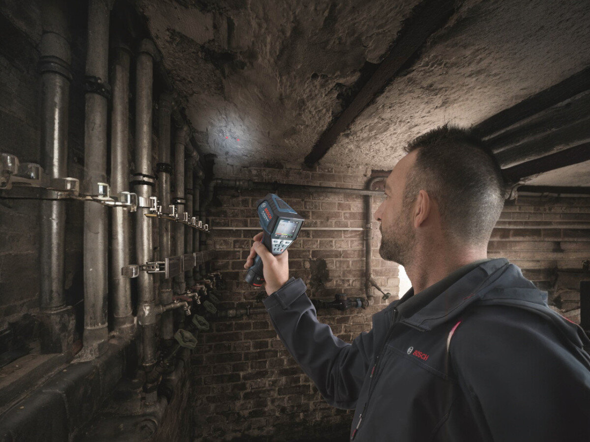 Termodetektor BOSCH Professional GIS 1000 C 0601083301, termodetektor, pomiar, ciepło, wilgoć, mężczyzna mierzy termodetektorem temperaturę sufitu w piwnicy