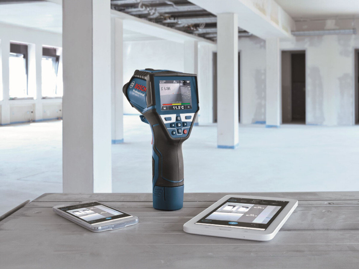 Termodetektor BOSCH Professional GIS 1000 C 0601083301, Bluetooth, aplikacja, smartfon, raport, termodetektor stoi na blacie w otoczeniu smartfonu i tabletu z aplikacjami GIS