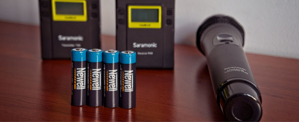 Akumulatorki AA 2500 mAh NEWELL (4 szt.), gotowość, łatwość, wygoda, oszczędność, Akumulatorki stoją pionowo na blacie w tle stacje ładowania i latarka