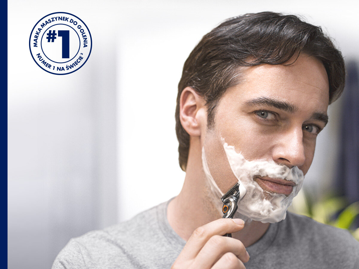 Wkład GILLETTE Fusion ProGlide (4 szt.) Mężczyzna goli twarz maszynką Gillette ProGlide, na policzku ma białą piankę do golenia. W lewym górnym rogu okrągły znaczek z tekstem 'MARKA MASZYNEK DO GOLENIA #1 NUMER 1 NA ŚWIECIE' w języku polskim.