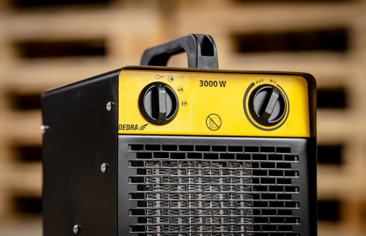 Nagrzewnica elektryczna DEDRA DED9931C1, chłodny, ciepły, gorący, wentylator, Panel sterowania z dwoma pokrętłami nagrzewnicy Dedra DED9931C1 na żółtym tle, widoczny uchwyt.