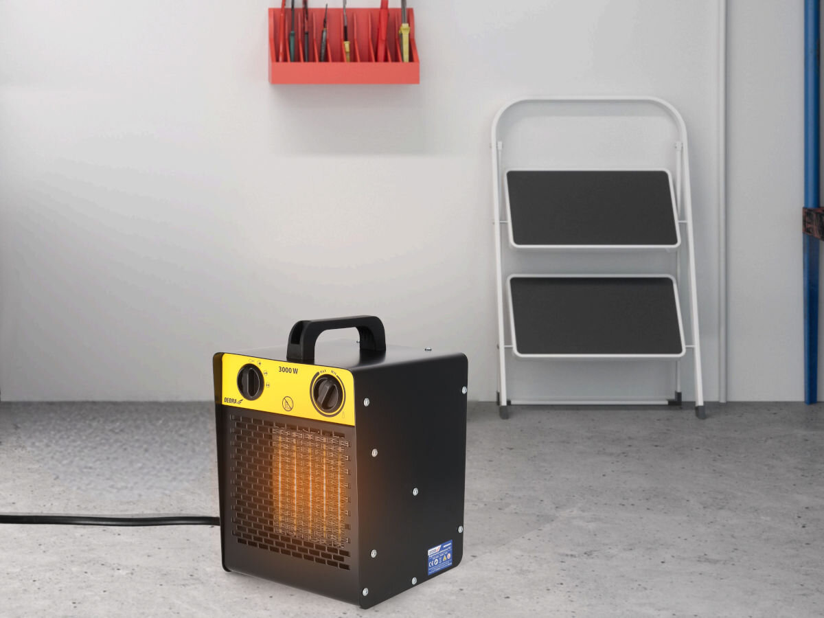 Nagrzewnica elektryczna DEDRA DED9931C1, przegrzanie, metal, IP20, ochrona, Nagrzewnica Dedra DED9931C1 pracuje w domu, widoczna jasna podłoga i ściany warsztatu.