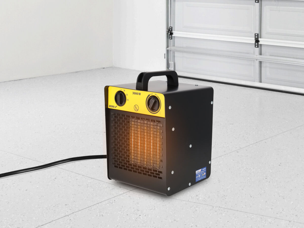 Nagrzewnica elektryczna DEDRA DED9931C1, ogrzewanie, osuszanie, nawiew, dystrybucja, Dedra DED9931C1 na garażowej podłodze, uruchomiona, widoczny żar ceramicznego elementu grzejnego.