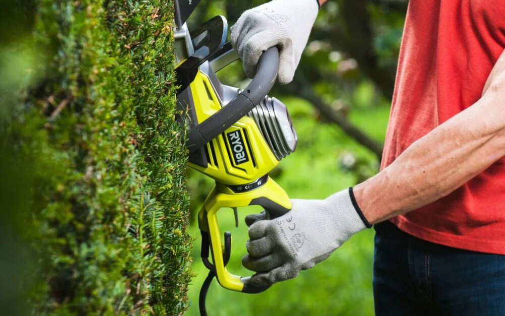 Nożyce do żywopłotu RYOBI RHT6760RL 600mm 0.65kW elektryczne ogród osoba przycina żywopłot w tle drzewa krzewy zbliżenie na silnik szczotkowy silnik o mocy 650 W stabilne i równomierne przenoszenie energii na ostrze płynność ruchów ogranicza konieczność wielokrotnego poprawiania prędkość ostrza na poziomie 1500 obr./min płynność pracy