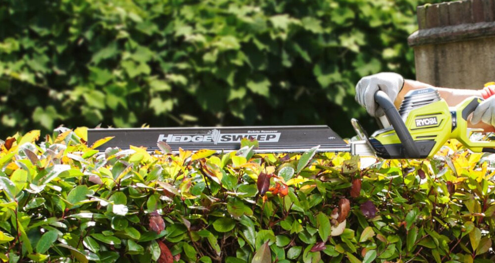 Nożyce do żywopłotu RYOBI RHT6760RL 600mm 0.65kW elektryczne ogród osoba przycina żywopłot nasadka HedgeSweep™ bieżące usuwanie ścinków z powierzchni żywopłotu podczas pracy porządek w ogrodzie skraca czas sprzątania poprawia komfort pracy