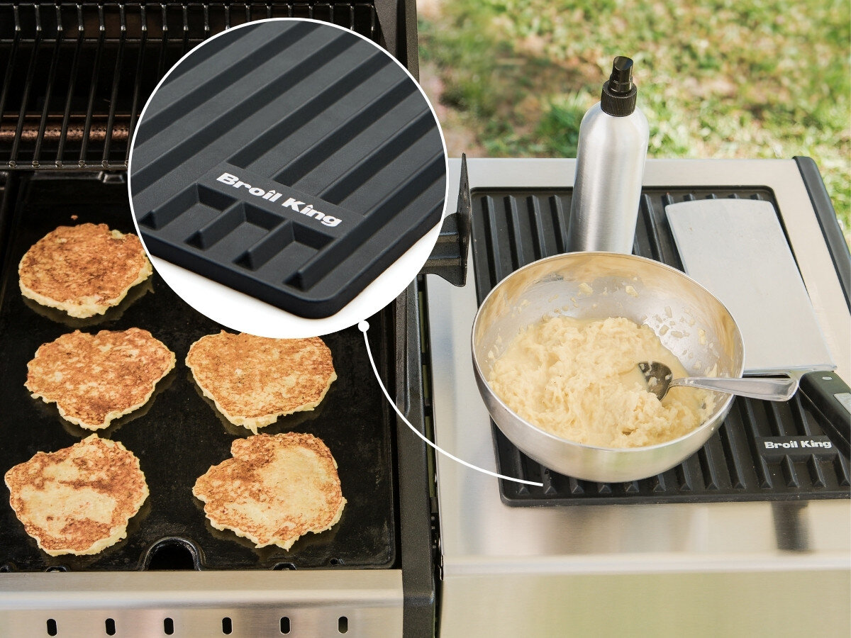 Na obrazie widoczny jest grill z sześcioma plackami oraz boczna półka z matą i miską z ciastem. Na macie widnieje napis \'Broil King\'.