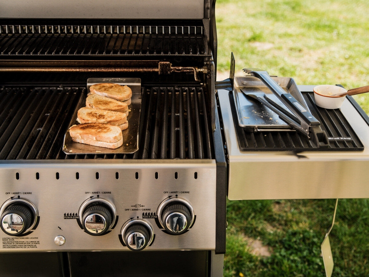 Zestaw do grillowania BROIL KING 64003, grill, kompletny, zestaw, narzędzia, Francuskie tosty na czarnej płycie ruszta grilla Broil King, obok narzędzi i małego garnuszka na bocznym stole.