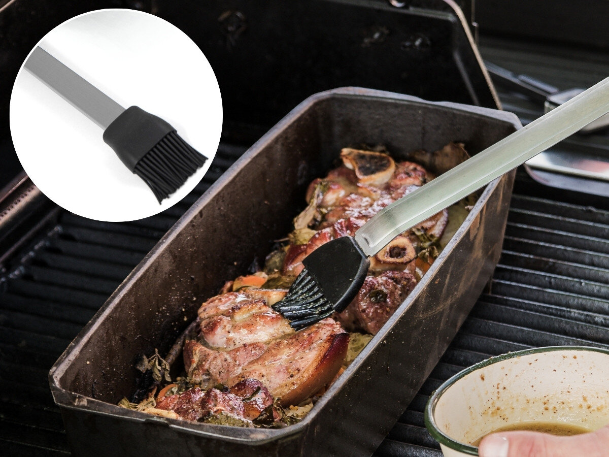 Zestaw do grillowania BROIL KING 64003, pędzelek, marynata, sos, natłuszczanie, Pędzelek silikonowy Broil King smaruje marynatą żeberka wieprzowe w czarnej blaszce na grillu obok miseczki z sosem.
