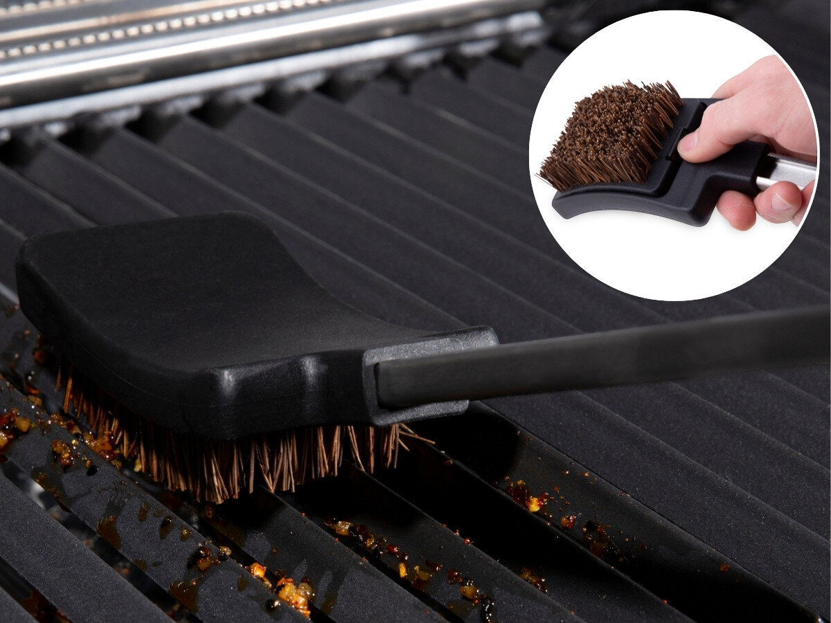 Zestaw do grillowania BROIL KING 64003, szczotka, ruszt, czyszczenie, włosie, Szczotka do czyszczenia grilla Broil King z wymienną główką zamiata resztki z czarnego rusu żeliwnego, z zbliżeniem na rękę wymieniającą główkę.