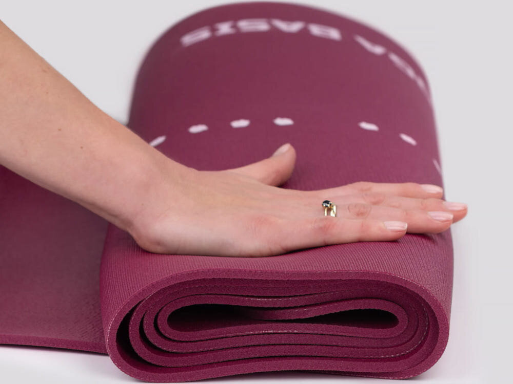Mata do jogi TIGUAR Yoga Basis Fioletowy jasne tło zwinięta mata osoba naciska na matę dłonią mieszanka gumy i PVC miękka i przyjemna w dotyku grubość 0,5 cm wyraźne odciążenie kolan, bioder i kręgosłupa