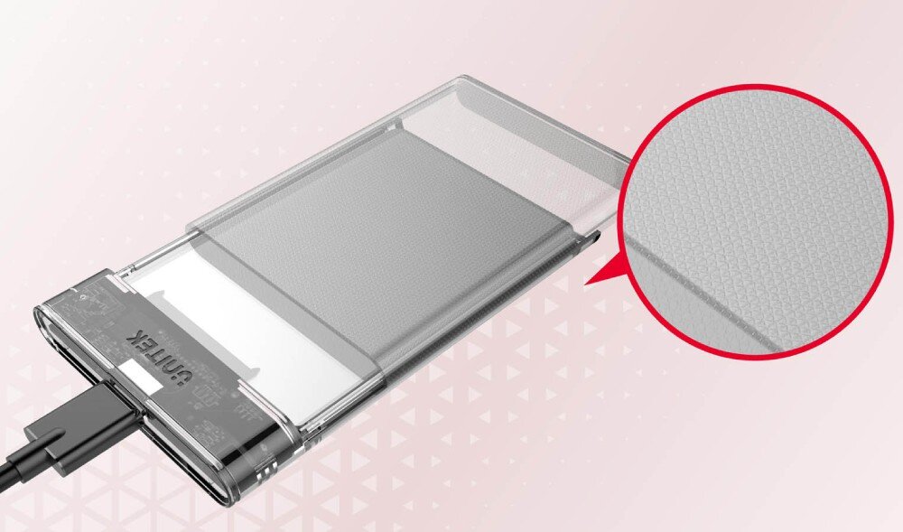 Obudowa dysku UNITEK S1103A Przezroczysta obudowa na dysk twardy leżąca skośnie na różowym tle z geometrycznym wzorem, z podłączonym czarnym kablem USB, a po prawej stronie w czerwonym kółku znajduje się zbliżenie na siateczkową teksturę powierzchni dysku wewnątrz obudowy
