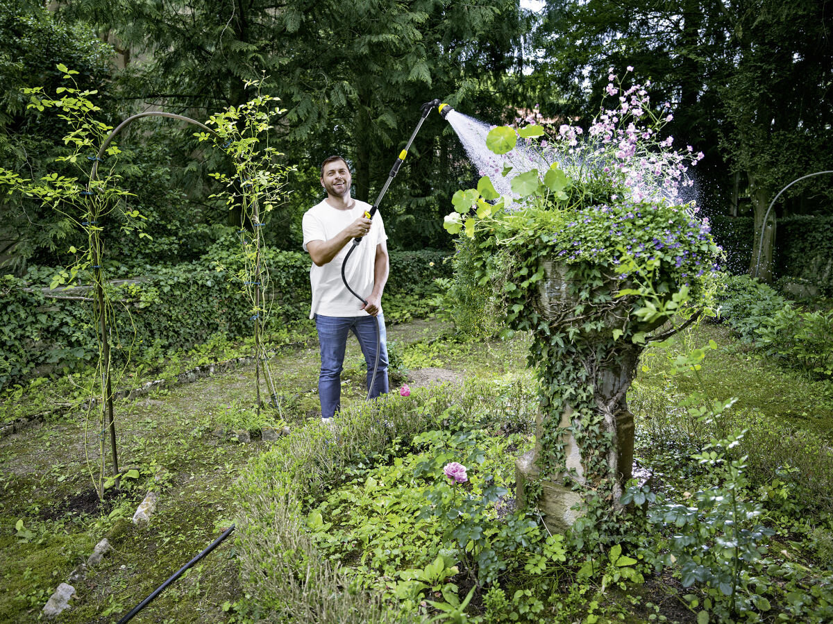 Wąż ogrodowy KARCHER PrimoFlex Premium 1/2 50 m 2.645-325.0, podlewanie, długość, transport, źródło, w tle ogród, mężczyzna podlewa drzewko w ogrodzie