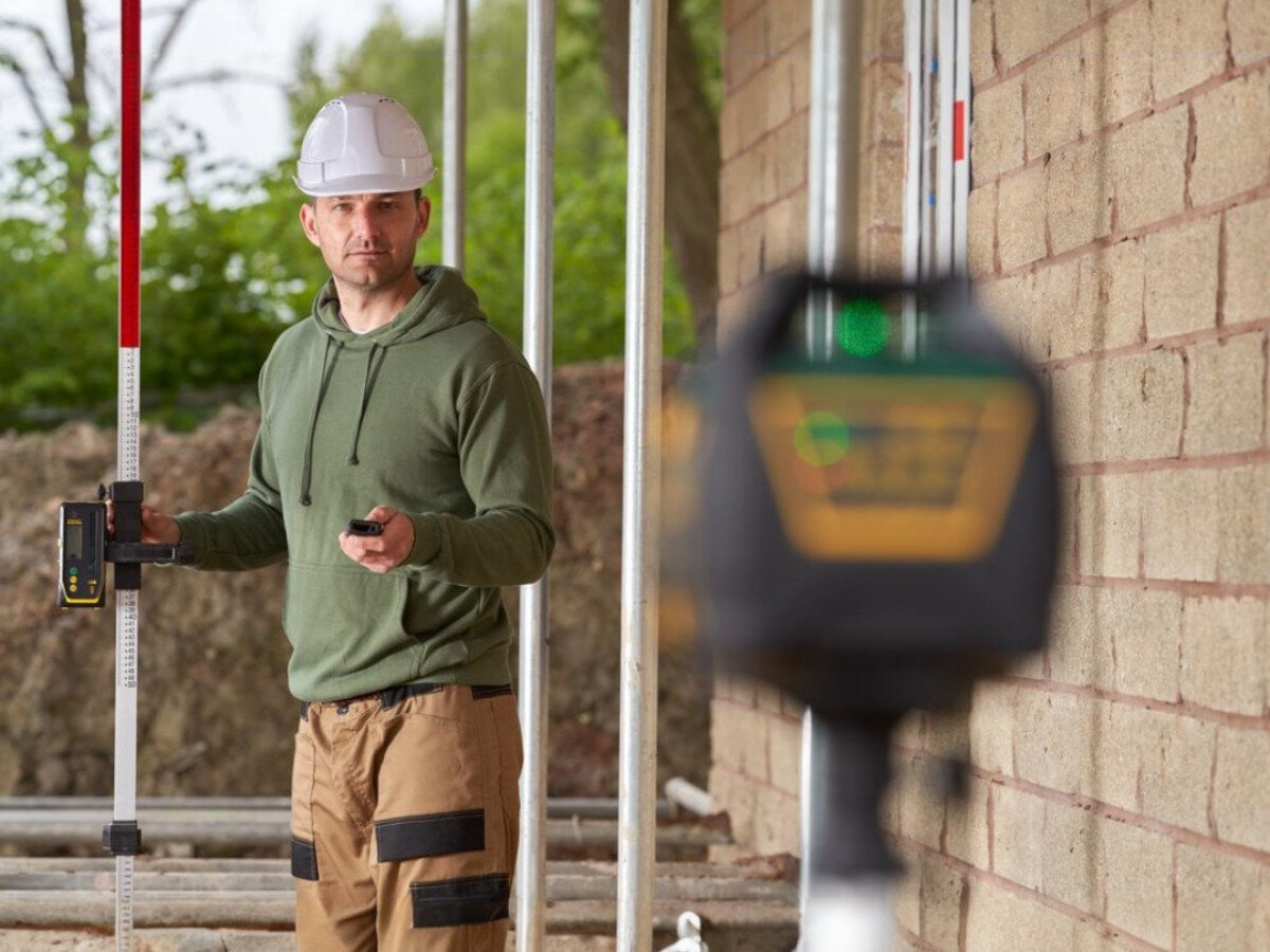 Niwelator laserowy STANLEY FMHT77448-1, laser, rotacyjny, zielony, poziomica, Niwelator laserowy na statywie ustawiony pod rusztowaniem.