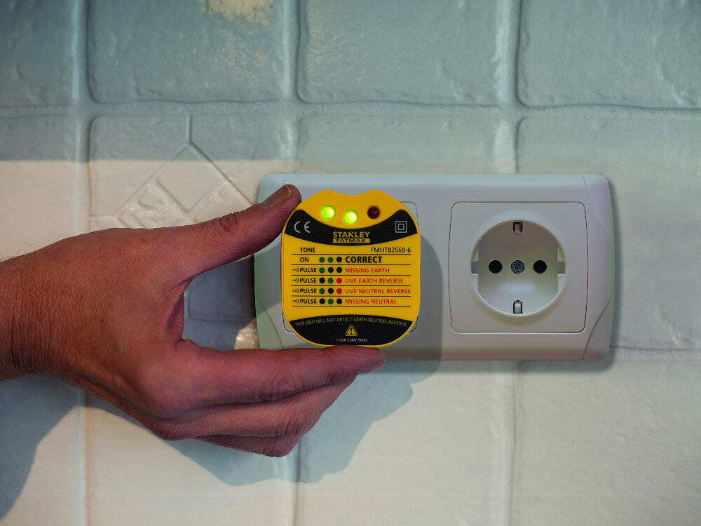 Tester prądu STANLEY FMHT82569-6, wskazania, uziemienie, faza, neutralny, Tester prądu STANLEY FMHT82569-6 wpięty do kontaktu i trzymany przez dłoń