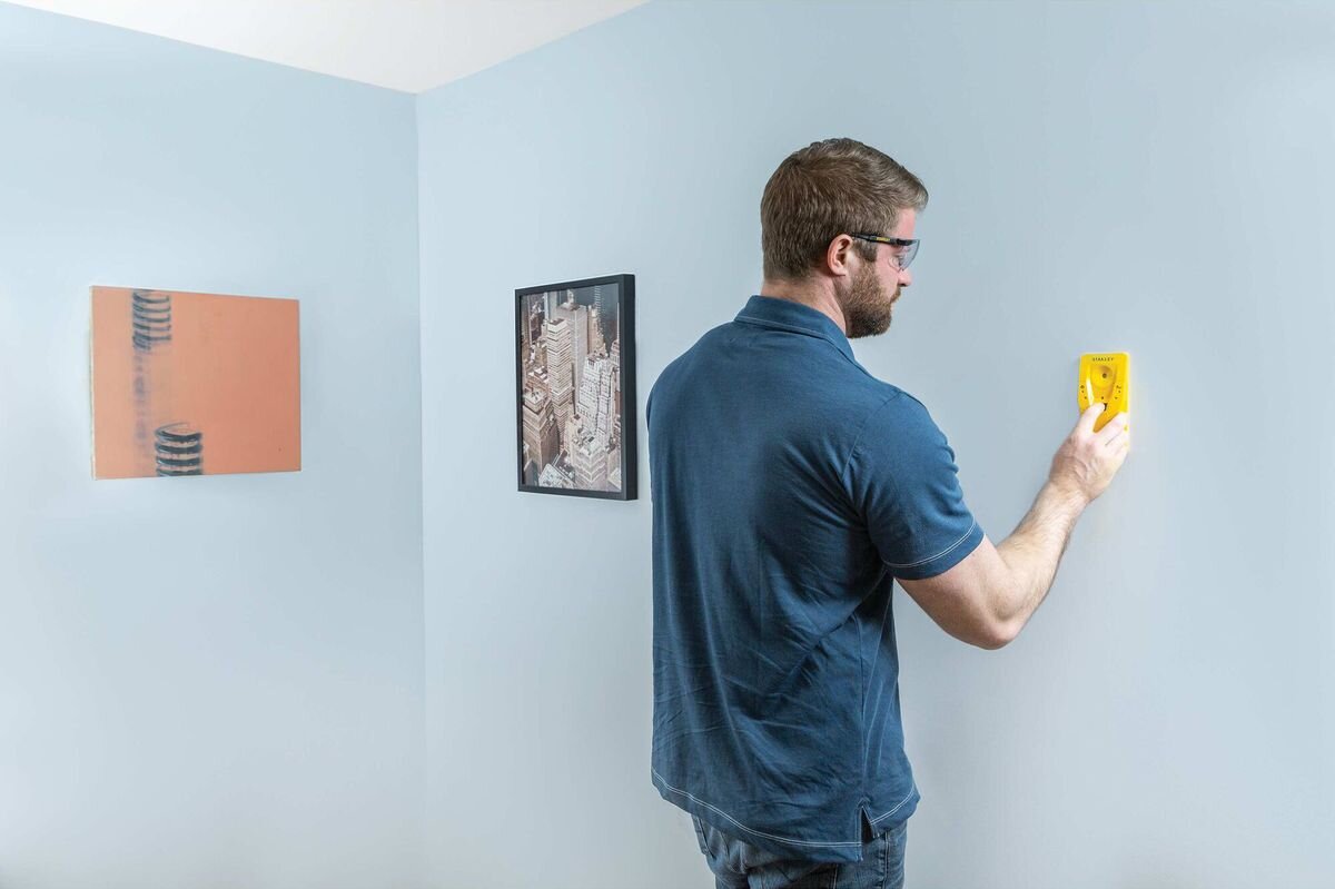 Wykrywacz profili STANLEY S110 STHT77587-0, profil, ściana, otwór, bezpieczeństwo, mężczyzna przykłada do ściany wykrywacz profili