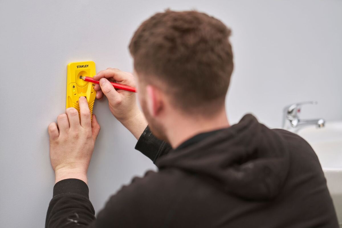 Wykrywacz profili STANLEY S110 STHT77587-0, wykrywanie, profil, drewno, metal, mężczyzna zaznacza ołówkiem miejsce wiercenia przy pomocy wykrywacza