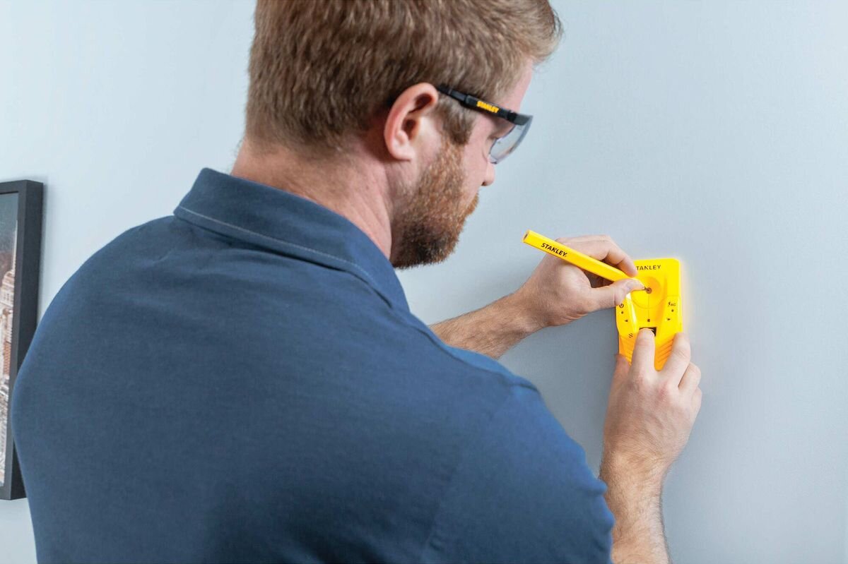 Wykrywacz profili STANLEY S110 STHT77587-0, kalibracja, waga, wymiary, obudowa, mężczyzna zaznacza punkt wiercenia przez wykrywacz profili