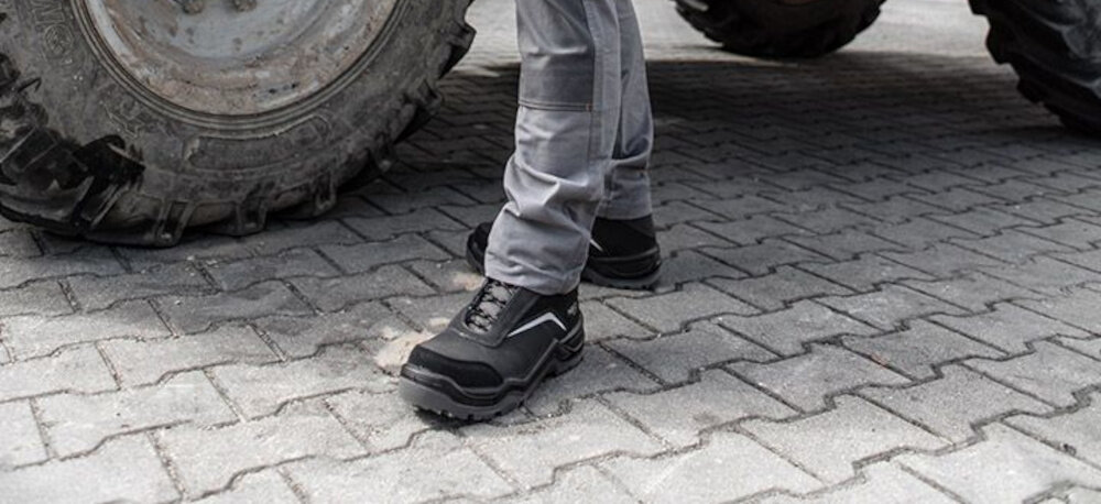 Buty robocze NEO 82-151-42 rozmiar 42 osoba stoi na chodniku bezpieczeństwo obuwie ochronne zabezpieczenieprzed urazami przemiękaniem poślizgami komfort wygoda
