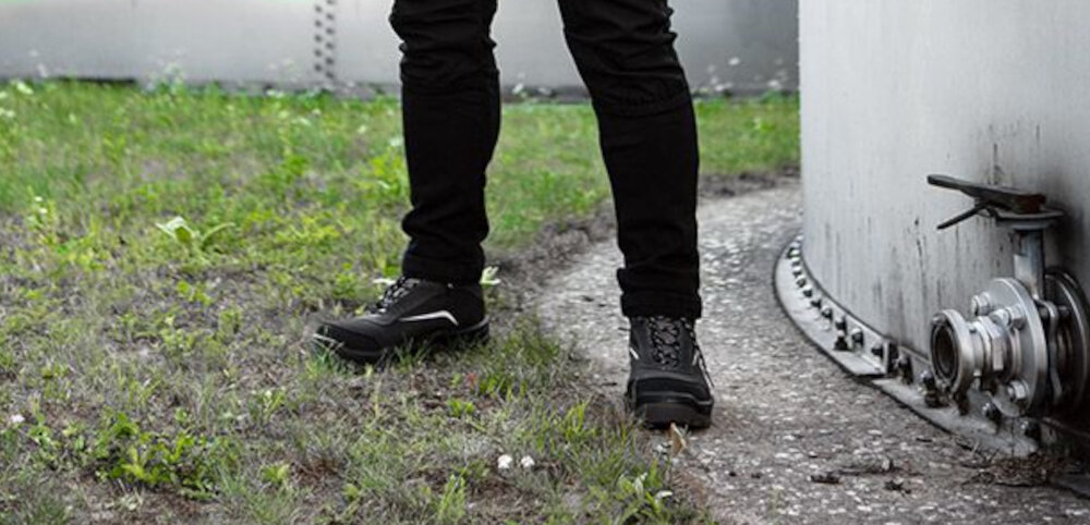 Buty robocze NEO 82-151-42 rozmiar 42 osoba stoi na trawie normy EN 20345 i EN ISO 20345:2022 wysoki standard ochrony certyfikat CE zgodność z rygorystycznymi europejskimi przepisami dla profesjonalistów i hobbystów