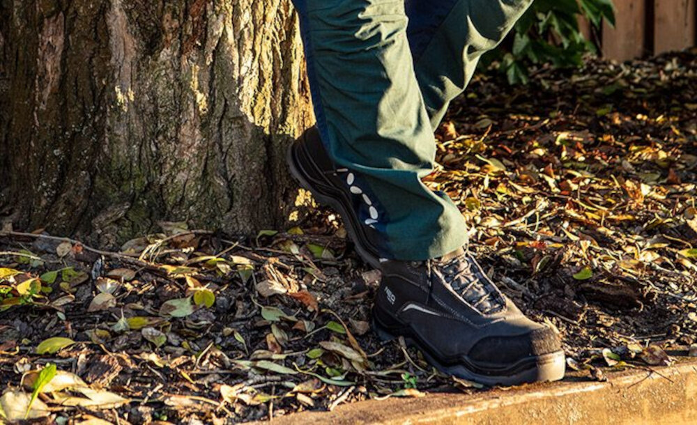 Buty robocze NEO 82-151-42 rozmiar 42 osoba opiera buty o pień drzewa z nubuku trwałość dobra oddychalność skutecznie zabezpiecza przed wilgocią podeszwa odporna na działanie olejów i smarów