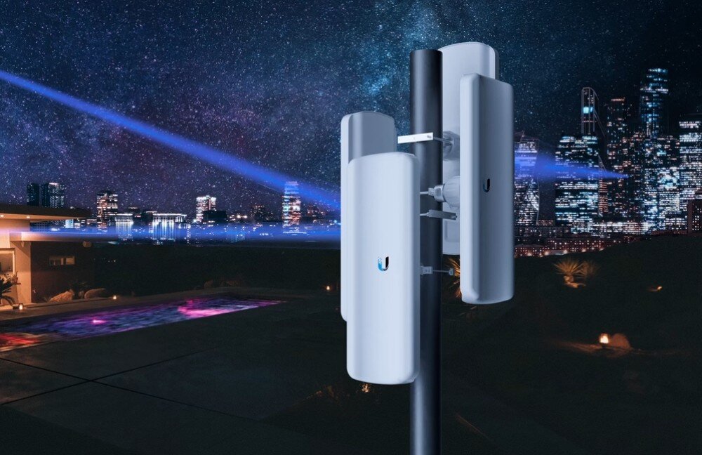 Punkt dostępowy UBIQUITI LAP-GPS 5 GHz, Wi-Fi Wizualizacja nocnego miasta z masztem, na którym zamontowane są urządzenia emitujące niebieskie wiązki sygnału, z gwiaździstym niebem w tle