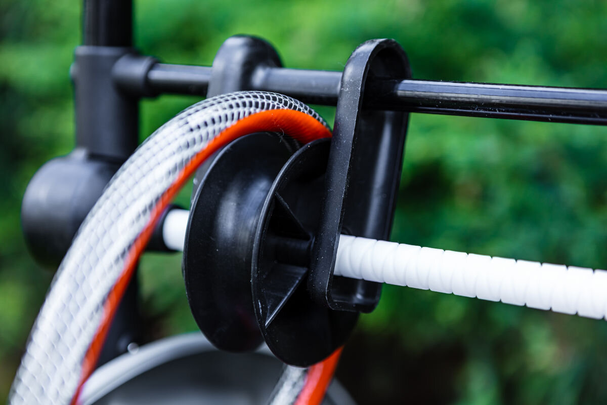 Wąż ogrodowy NEO Professional 3/4 20 m 15-843, skręcanie, załamania, system, żywotność, na roślinnym tle część węża zawija się wokół owijarki