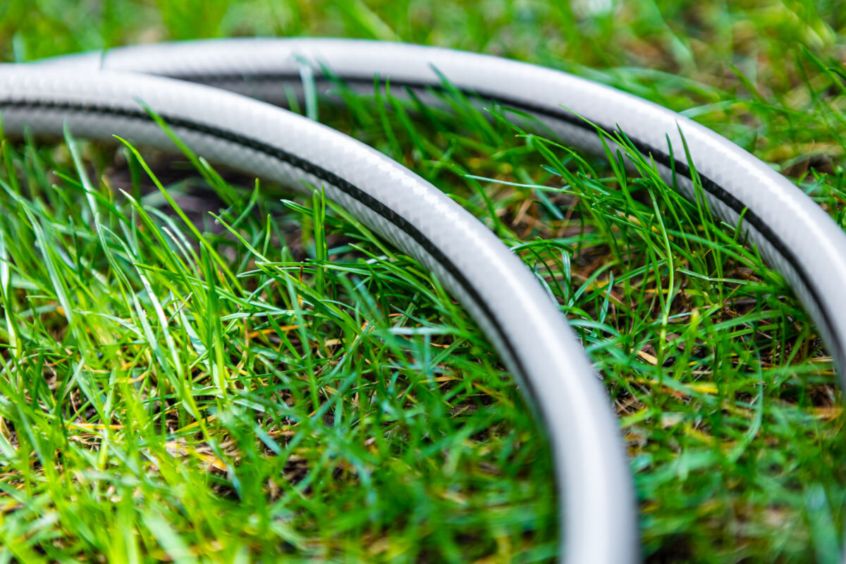 Wąż ogrodowy NEO Optima 3/4 50 m 15-825, zastosowanie, ciśnienie, bar, wytrzymałość, w tle trawnik, na ziemi leży wąż w 2 częściach