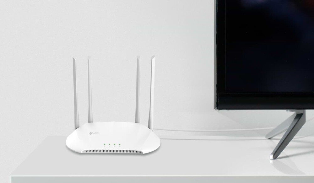 Punkt dostępu TP-LINK TL-WA1201 Router stojący obok telewizora na białym meblu, łączność Wi-Fi, pasma, prędkość