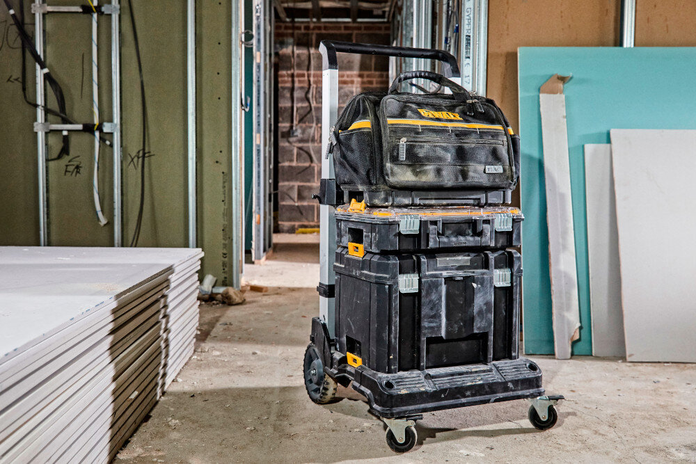Torba narzędziowa DEWALT DWST82991-1 plac budowy pomieszczenie płyty kartonowo-gipsowe torba ustawiona na skrzynkach narzędziowych połączona z innymi modułami TSTAK możliwość budowania zestawów dopasowanych do indywidualnych potrzeb stabilne i wygodne przewożenie większej ilości sprzętu
