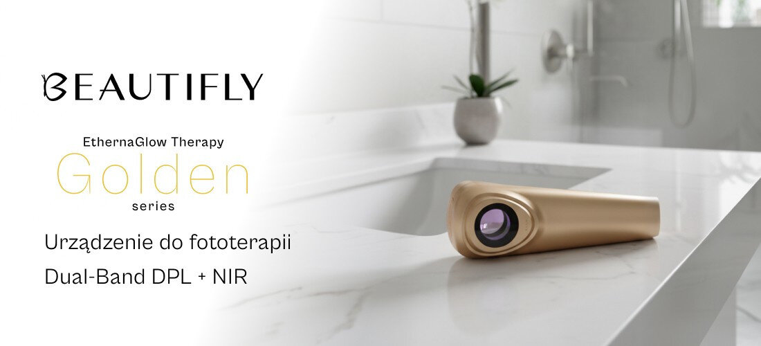 Na blacie łazienkowym leży złote urządzenie do fototerapii. Obok widoczny jest tekst: \'BEAUTIFLY EternaGlow Therapy Golden series Urządzenie do fototerapii Dual-Band DPL + NIR\'.