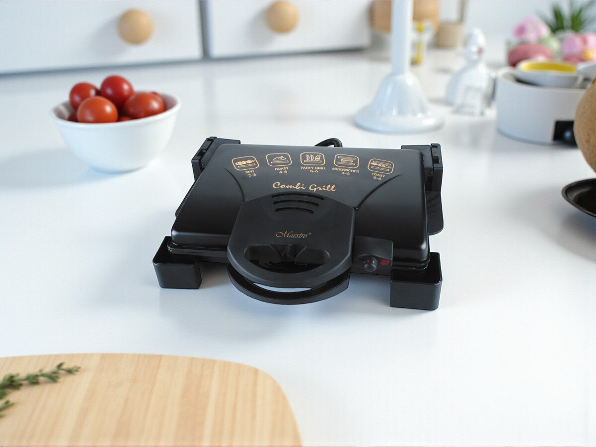 Grill elektryczny MAESTRO MR-717, stabilność, nóżki, antypoślizgowe, płyty, grill stoi w kuchni na blacie w tle potrawy i deska do krojenia