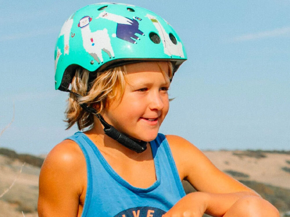 Kask HORNIT Lama Błękitny dla Dzieci (rozmiar S) dziecko w kasku na tle nieba w rozmiarze S regulowany zakres obwodu bezpieczne i pewne noszenie system regulacji w zakresie od 48 do 53 cm kask rośnie wraz z dzieckiem