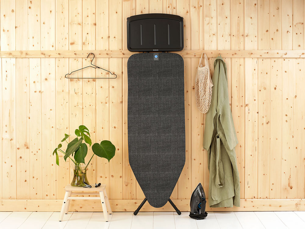 Deska do prasowania BRABANTIA 134746 Denim Black 124 x 45 cm ułatwienie prasowania deska stoi oparta o ścianę ciemny pokrowiec czarna podstawka czarne nóżki