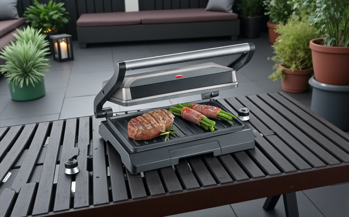 Grill elektryczny SEVERIN KG 2394, grillowanie, gotowanie, smażenie, ogród, grill stoi na drewnianym stole na tarasie frontem lewo skos