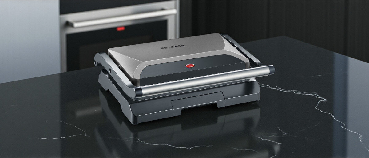 Grill elektryczny SEVERIN KG 2394, nagrzewanie, płyta, obróbka, termiczna, na kuchennym kamiennym blaciew kuchni stoi grill frontem lewo skos