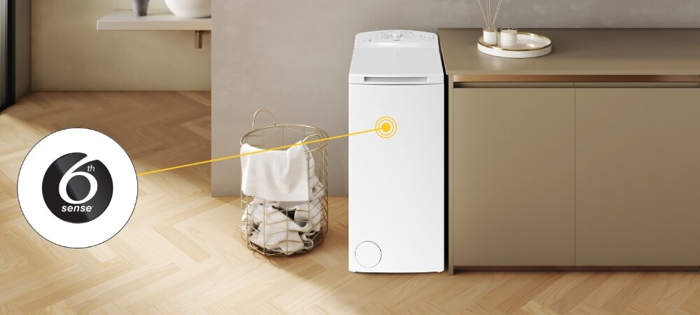 Na obrazie znajduje się biała pralka ustawiona obok szafki w jasnym pomieszczeniu. Obok pralki widoczny jest kosz z praniem, a na obrazie znajduje się logo \'6th sense\'.