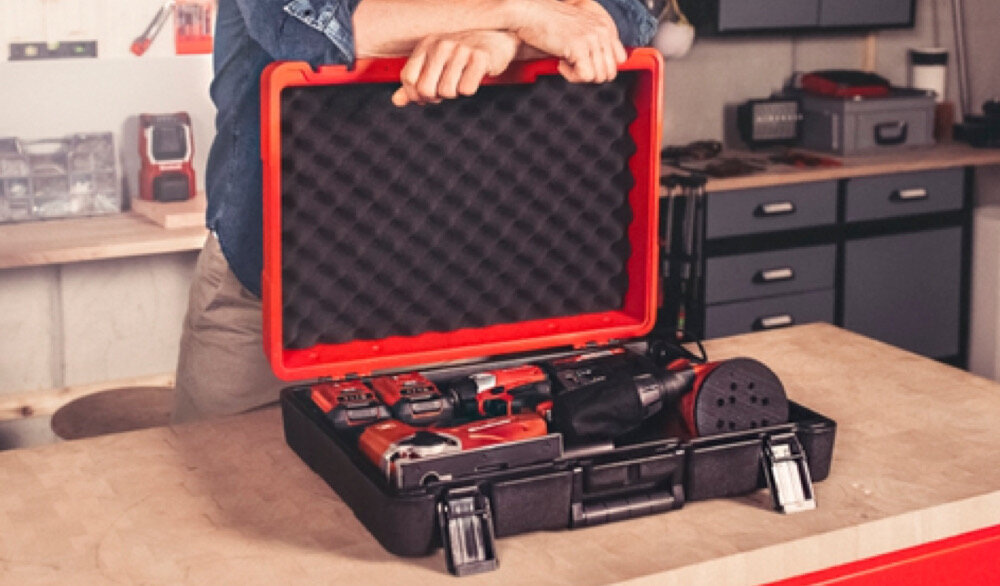Walizka narzędziowa EINHELL E-Box M55-40 pomieszczenie osoba opiera się o walizkę walizka wypełniona narzędziami w tle ściana na ścianie narzędzia przechowywanie organizacja pracy uniwersalna zastosowanie