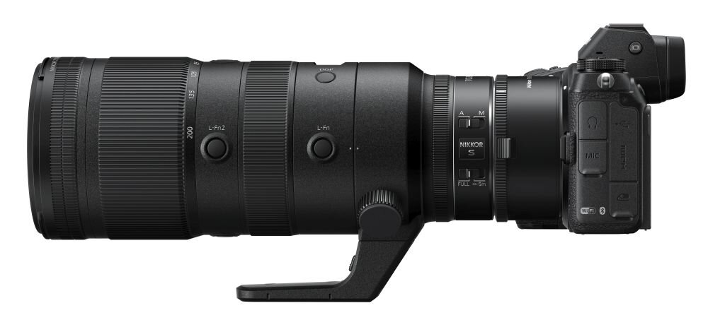 Na obrazie widoczny jest czarny obiektyw fotograficzny z kilkoma pierścieniami regulacyjnymi i przyciskami. Na obiektywie znajduje się napis \'NIKKOR S\'.