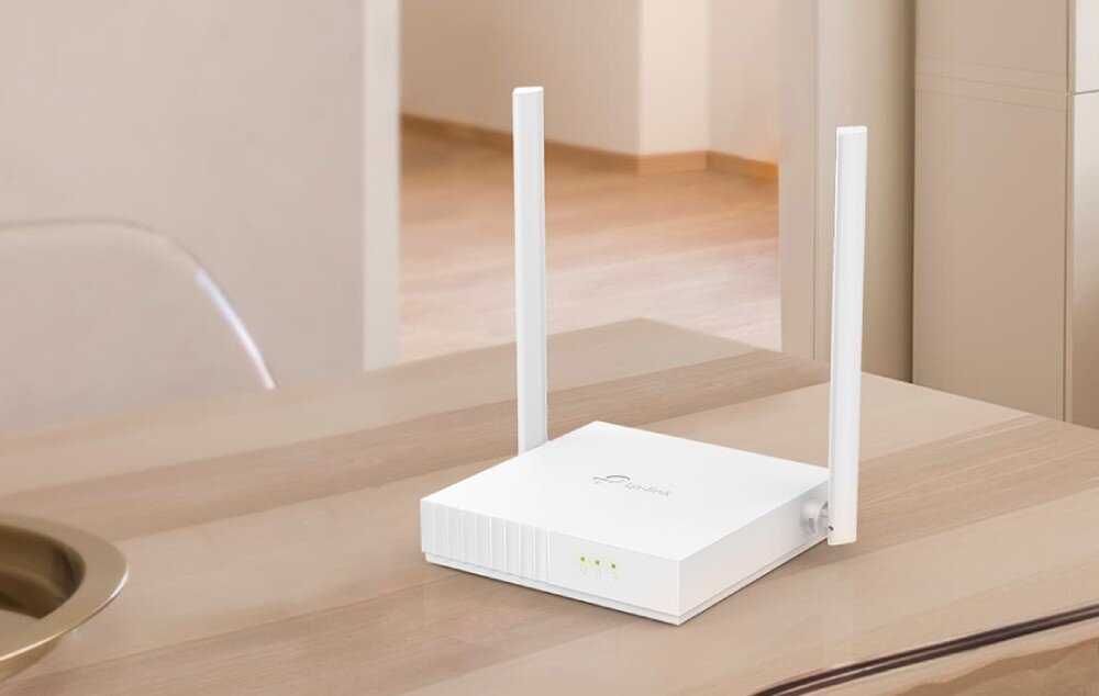 Router TP-LINK TL-WR820N Biały router z dwiema antenami ustawiony na jasnym stole obok ceramiki dekoracyjnej na tle szarej ściany, opis