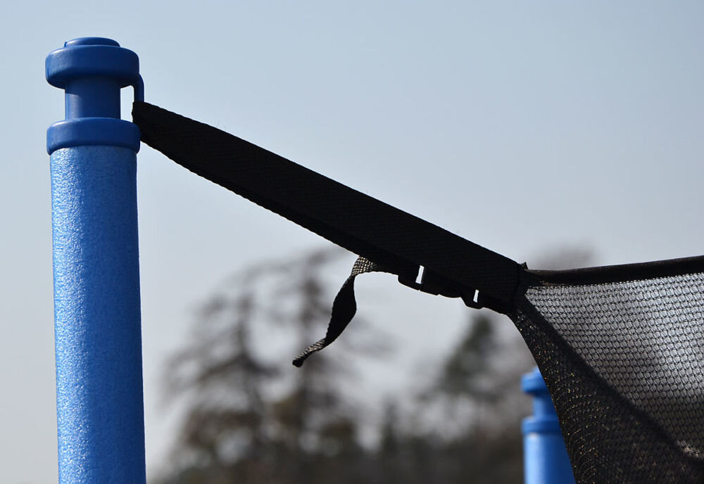 Trampolina ENERO FI 244 cm, udźwig, dzieci, dorośli, aktywność, Zbliżenie na jeden ze słupków trampoliny, do którego jest przymocowany sznurek siatki