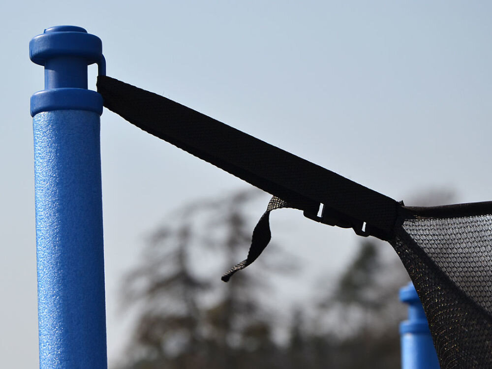 Trampolina ENERO FI 305 cm, nogi, U, podparcie, stabilność, Zbliżenie na jeden ze słupków trampoliny, do którego jest przymocowany sznurek siatki