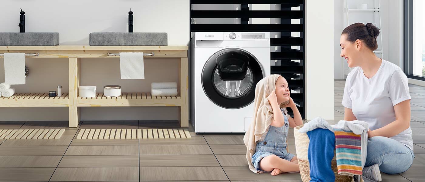Nowoczesna łazienka z kamiennymi umywalkami i pralką Samsung, mama i córka bawiące się na podłodze ubraniami z kosza na pranie Nowoczesna łazienka z kamiennymi umywalkami i pralką Samsung, mama i córka bawiące się na podłodze ubraniami z kosza na pranie