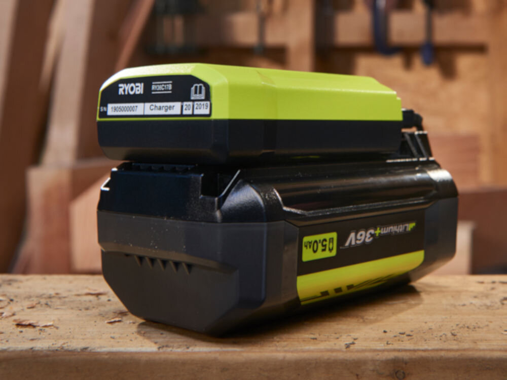 Ładowarka RYOBI RY36C17A 36V 1.7A, energia, akumulator, Akumulator stoi na blacie warsztatowym, w tle warsztat