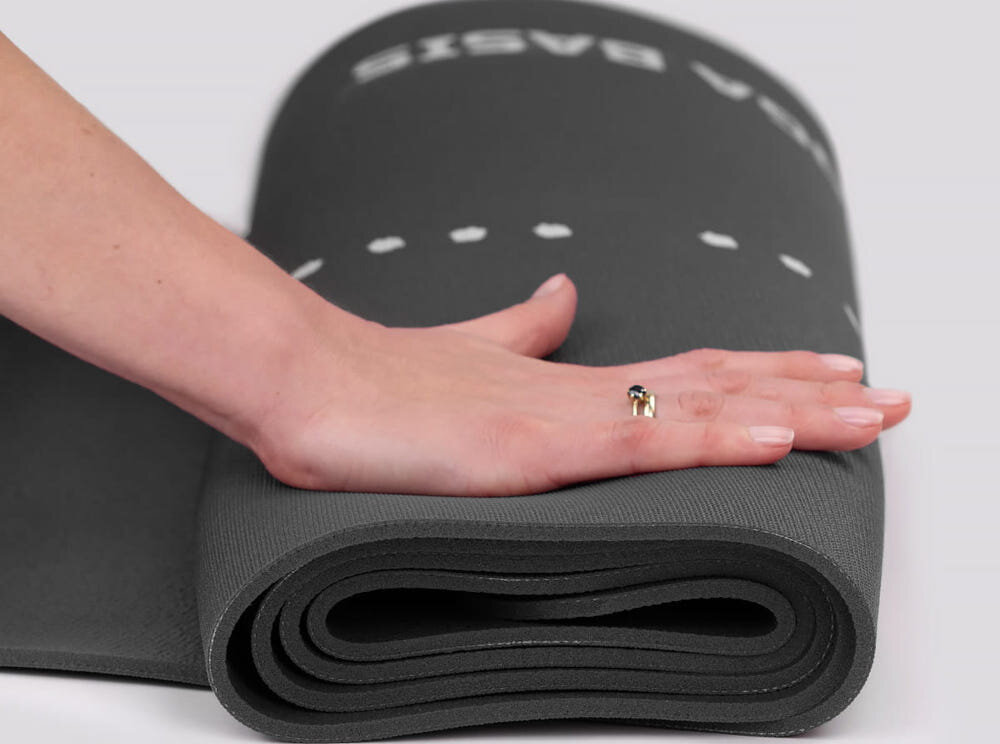 Mata do jogi TIGUAR Yoga Basis Grafitowy jasne tło zwinięta mata osoba naciska na matę dłonią mieszanka gumy i PVC miękka i przyjemna w dotyku grubość 0,5 cm wyraźne odciążenie kolan, bioder i kręgosłupa