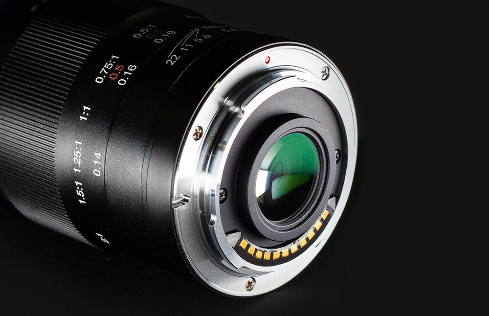 Obiektyw VENUS OPTICS LAOWA 50mm f-2.8 2x Ultra Macro do Micro 4-3 Zbliżenie tylnej części czarnego obiektywu z metalowym bagnetem i widocznymi stykami, na czarnym tle