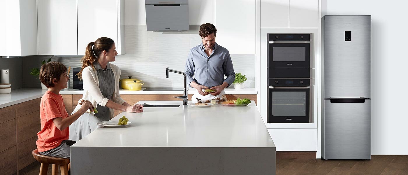 Dwójka rodziców i synek siedzą w kuchni przy wyspie przygotowując śniadanie